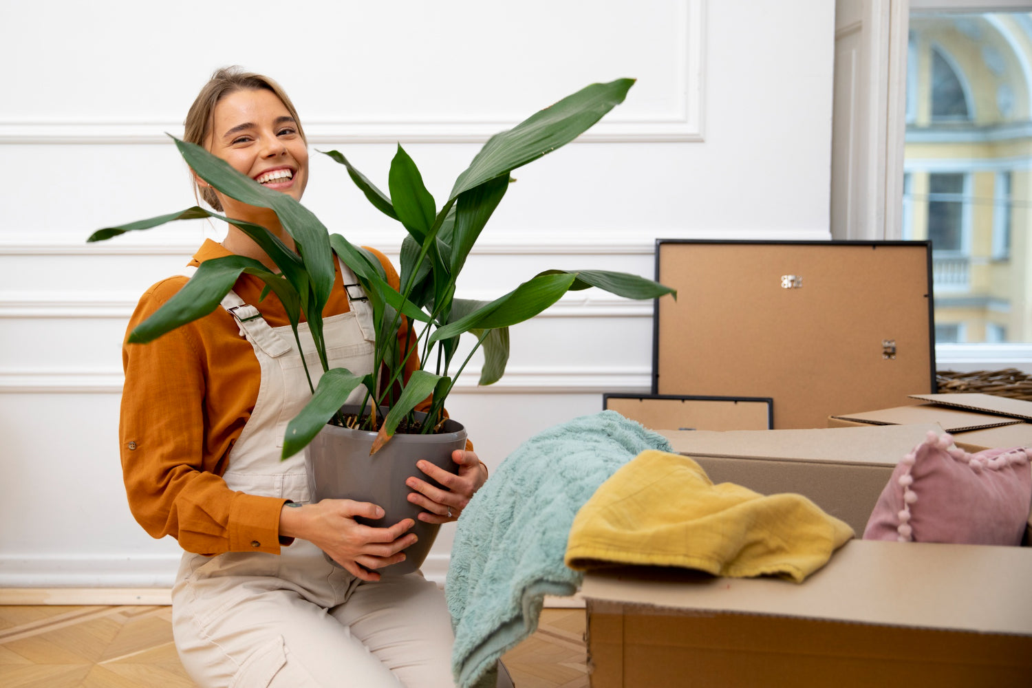 woman holding potted plant in beige pot moving into new home