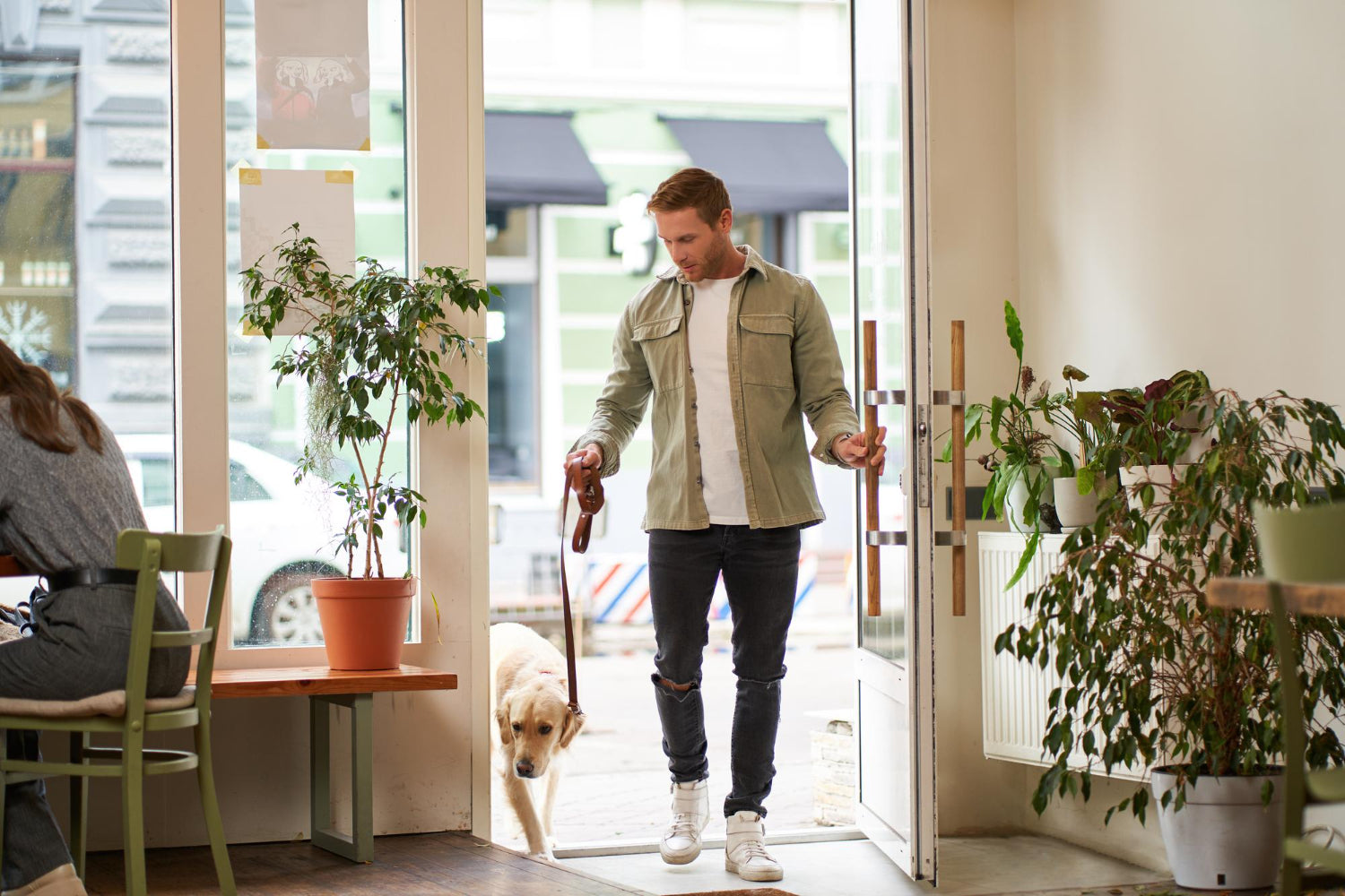 man with dog in leash entering coffee shop with potted plants - Plant Studio